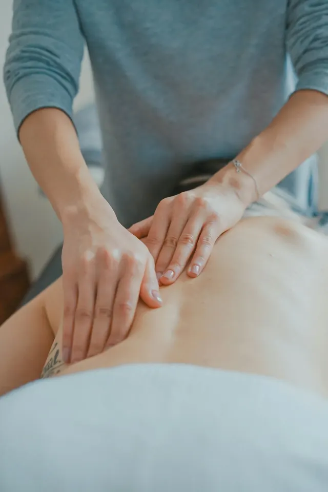 A registered massage therapist working on a client's back on a treatment table